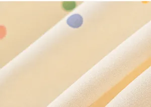 Close-up detail of beige windbreaker fabric with colorful polka dot patterns.