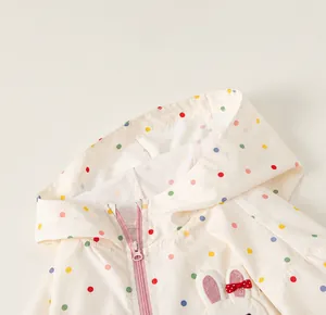 Detail view of children's windbreaker featuring a polka dot pattern and protective hood.