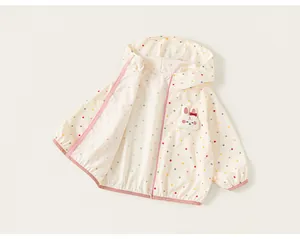 Detail view of girls' cream polka dot hooded windbreaker with a cute rabbit badge