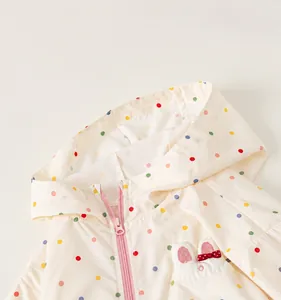 Close-up of child's hooded windbreaker featuring colorful polka dots and pink zipper