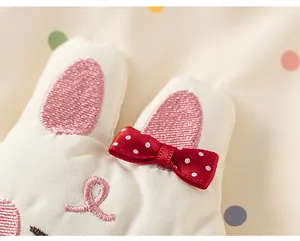 Close-up detail of cute rabbit embroidery and red bow on polka dot girls windbreaker