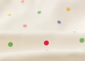 Detailed macro view of soft white windbreaker fabric featuring colorful polka dot pattern