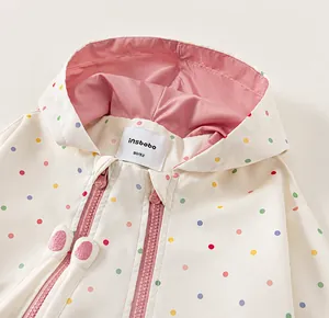 Detail close-up of a toddler girl's white polka dot windbreaker with pink lining and hood