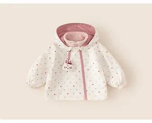 Close-up of girl's white windbreaker jacket with colorful polka dots and cute rabbit charm