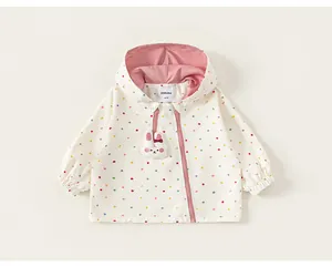 Close-up of white polka dot toddler windbreaker with pink hood and rabbit patch