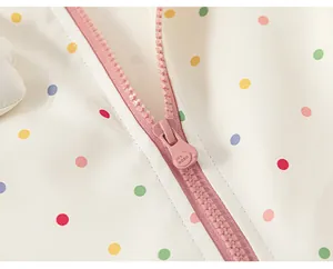 Close-up of a high-quality pink zipper and colorful polka dot fabric on a kids windbreaker jacket.