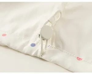 Close-up detail of adjustable drawstring toggle and polka dot fabric on child's windbreaker