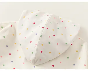 Close-up detail of a white children's hooded windbreaker with colorful polka dots