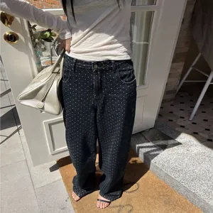 Vue détaillée d'un pantalon en jean noir à pois à jambes larges porté par un mannequin
