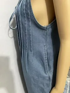 Close-up of pleated details and side pockets on a washed denim jumpsuit