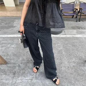 Détail d'un jean noir à pois pour femme avec jambe large porté en extérieur urbain