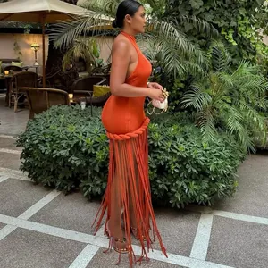 Dettaglio di un sexy abito longuette arancione bruciato con frange in un giardino estivo.