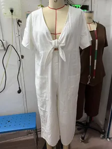 Close-up detail of a white V-neck short sleeve denim jumpsuit with a front tie-knot