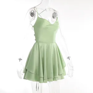 Detail view of a light green satin backless dress with lace-up straps and tiered A-line skirt