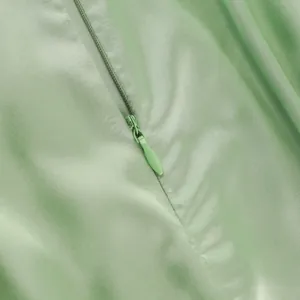 Detailed close-up of light green satin dress showing high-quality hidden zipper