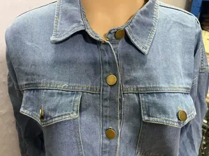 Détail d'une chemise en jean bleu délavé avec des boutons métalliques et poches avant