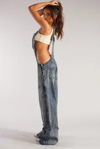 Detail view of loose denim overalls with side pockets in a vintage wash finish.