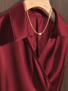 Elegant burgundy satin blouse detail showing smooth fabric texture and V-neck collar