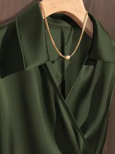Detailed macro shot of a deep olive green satin blouse with a lustrous silk-like texture.