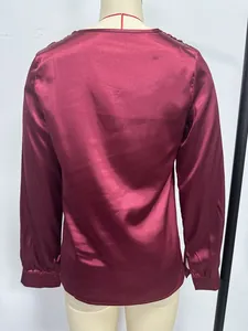 Detailed back view of a burgundy red long-sleeved satin blouse displayed on a mannequin