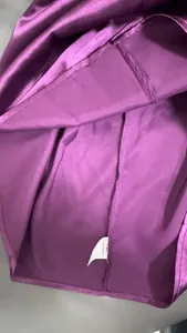 Nahaufnahme der Innenseite eines lila Satintops mit Naht und 100% Polyester Etikett