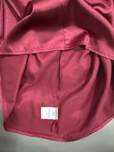 Detail shot of burgundy satin shirt with 100% polyester care label and S size tag