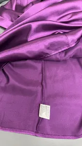 Primo piano dettagliato della trama del raso viola e dell'etichetta di cura
