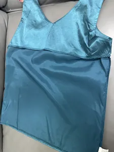 Detailansicht eines petrolfarbenen Satin-Tops mit V-Ausschnitt, das die glatte Stofftextur zeigt.