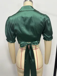 Back view of emerald green satin cropped top with puff sleeves and tie-back bow detail