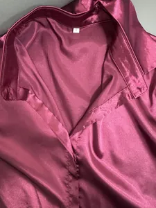 Macro view of a maroon satin shirt collar highlighting glossy fabric and size S tag