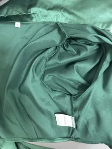 Close-up showing internal stitching and fabric care label of a green satin crop top.