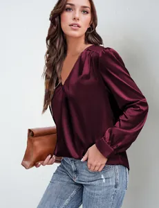 Dettaglio dell'elegante camicia di raso bordeaux con scollo a V e maniche lunghe.