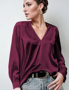 Dettaglio della camicetta in raso bordeaux con scollo a V e raffinato design a pieghe