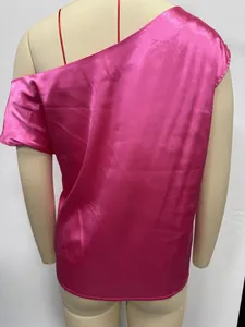 Macro detail view of fuchsia pink satin one-shoulder blouse on mannequin display