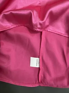 Detail of hot pink satin fabric and 100% polyester wash label on a sleeveless shirt