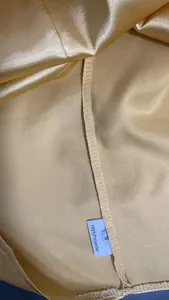 Macro detail of golden satin fabric with 100% polyester wash label and size S tag