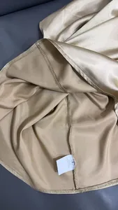 Detailansicht der Nähte und des Waschetiketts aus 100 % Polyester an einer Satinbluse