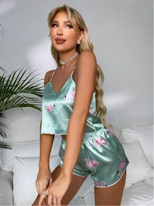 Close-up view of the mint green satin pajama set with flamingos worn by a model