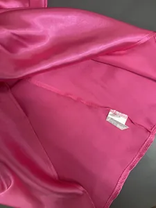 Close-up of pink satin fabric texture and clothing care label with stitching details