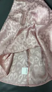 Detailansicht aus rosa Satin mit Leopardenmuster und 100 % Polyester-Pflegeetikett
