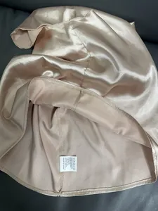Close-up detail of the care label and interior stitching of a champagne satin top