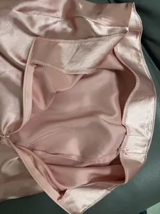 Detailansicht des Reißverschlusses und der Nähte eines rosa Satin-Midirocks in hoher Qualität