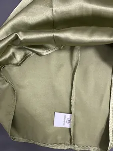 Gros plan de l'étiquette de composition 100 % polyester sur un haut en satin vert