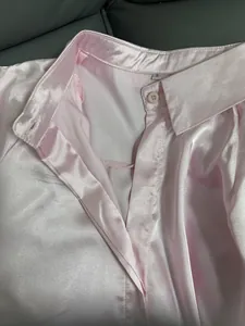 Detailed view of a pink satin shirt showing the collar, size label, and silky fabric