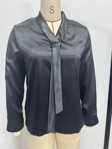 Gedetailleerd overzicht van zwarte satijnen blouse met V-hals en een elegante das.