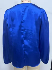 Vista posterior detallada de una blusa de satén azul real de manga larga en un maniquí