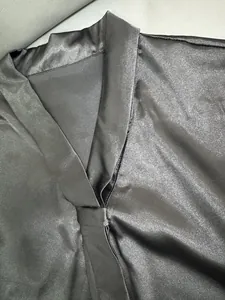 Detailopname van een zwarte satijnen blouse met V-hals en elegant strikdetail