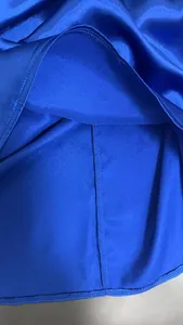 Detalle de tela de satén azul real con enfoque en textura suave y costura del dobladillo