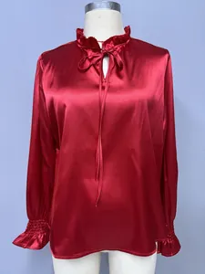 Macro detail of the elegant red satin blouse showing ruffled collar and tie neck