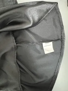 Detailopname van het waslabel van een zwart satijnen shirt van 100% polyester.